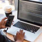 App Development - Person Holding Smartphone while using Laptop
