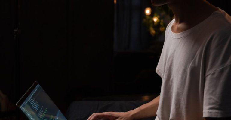 Remote Work - Side View of a Man in a Beanie Using a Laptop