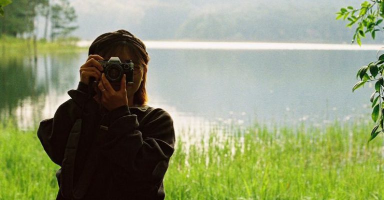 Note-Taking - A woman taking a photo of a lake