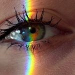 Mind Mapping - Closeup of crop anonymous sad female with green eyes and rainbow light on face looking at camera